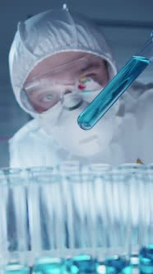 Scientist Holding Test Tube of Blue Liquid Amidst Numerous Others in Lab