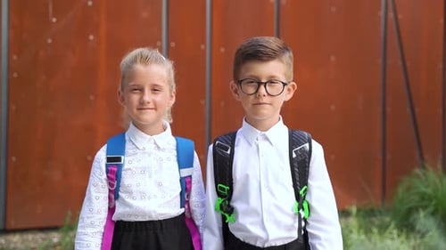 Smiling Students Wearing Backpacks Stand in Schoolyard