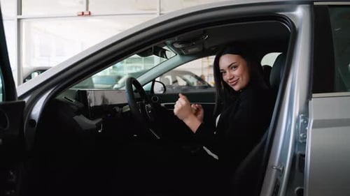 Happy Businesswoman Enjoying New Car in Dealership