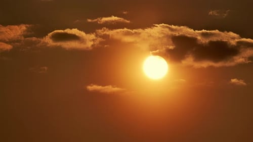 Großer Sonnenuntergang durch Wolken, Zeitraffer, große Sonne, schnell untergehender UHD-Teleobjektiv