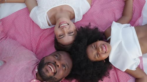 4K Portrait of African family relaxing together at the beach on summer vacation.