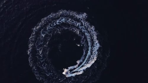 Boat spinning in the ocean aerial top view