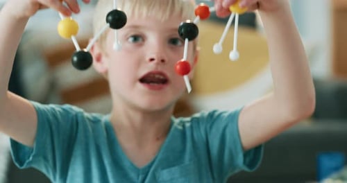 Boy Plays with Colorful Molecule Model at Home