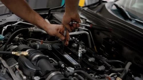 Mechaniker arbeitet unter der Motorhaube eines Autos in einer Werkstatt