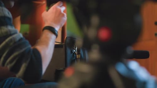 Studio Guy Reaching Into Camera Equipment Bag on Table While Adjusting Camera Gear
