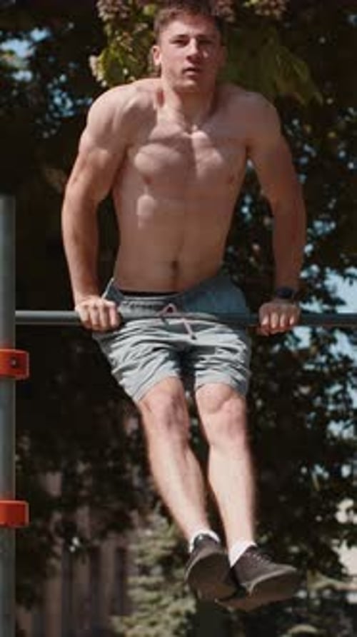 Muscular Man Doing Pull-Ups in Outdoor Park