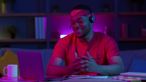 Man in Headset Talking on Laptop at Desk