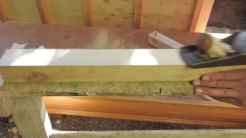 Ein Schreiner, der einen schwarzen hält Flugzeug in seinen Händen und bearbeitet in seiner fliegenden Hand ein Holzbrett
