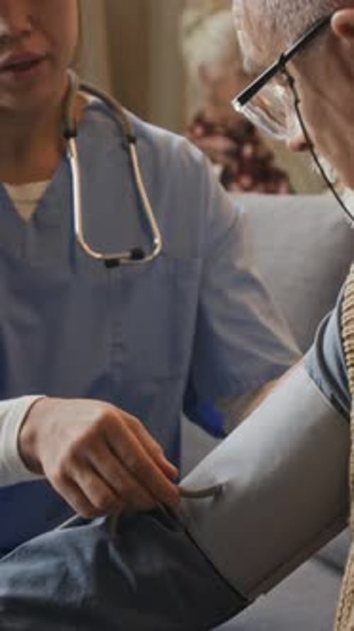 Woman Doctor Taking Senior Man's Blood Pressure at Home