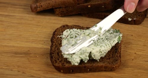 Spreading Herb Cream Cheese on Dark Rye Bread