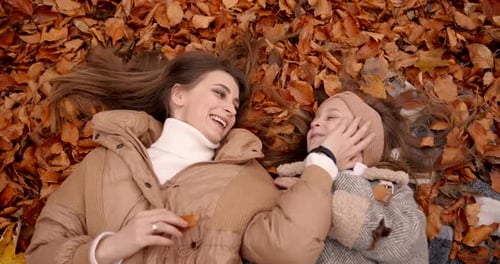Top View of Mom and Daughter Lying Among Fallen Leaves