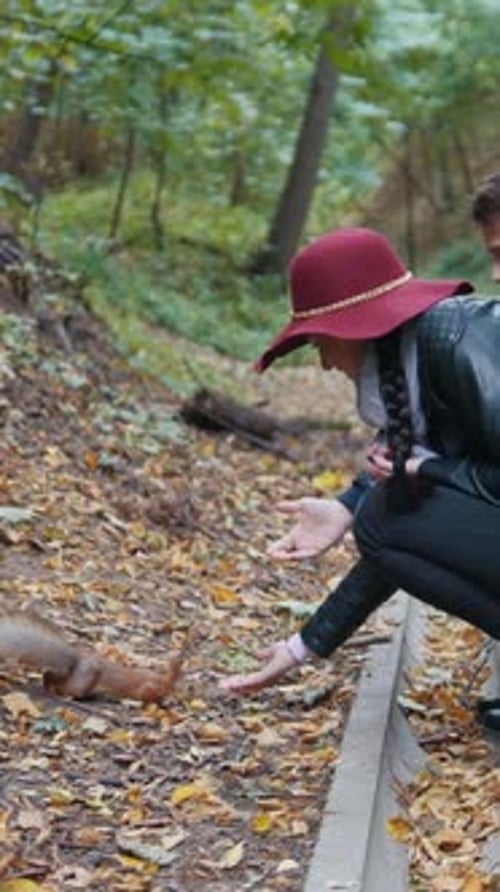 Young Man and Woman Feeding Squirrel in the Park From