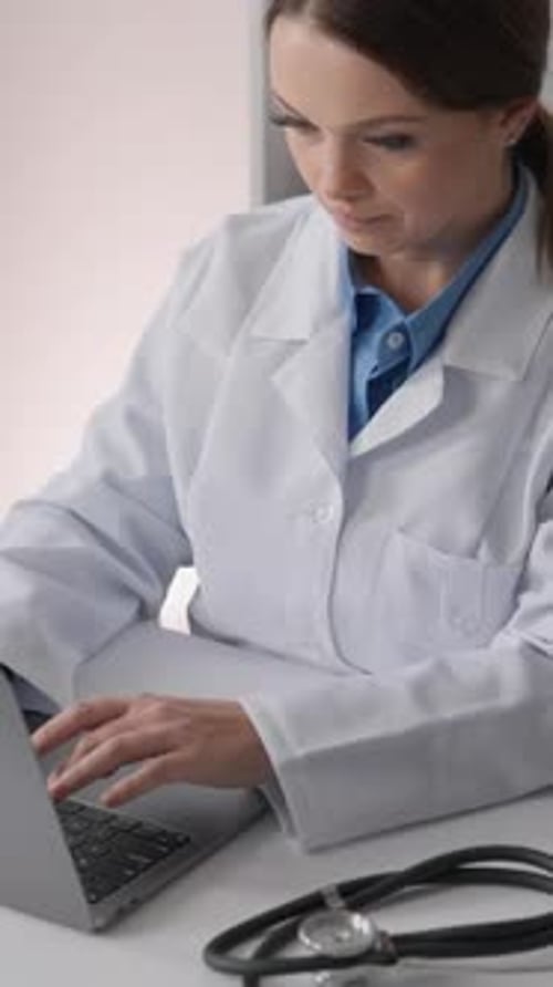 Woman Doctor Typing on Laptop in Office