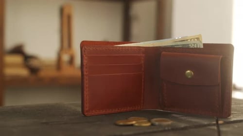 Open Leather Wallet on Wooden Table with Cash