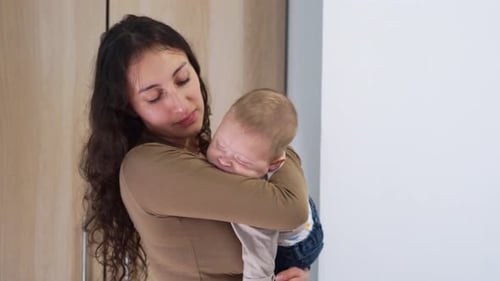 Woman Holding Sleeping Baby in Arms Indoors