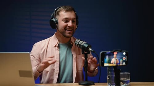 Young Man Talking Into Microphone Recording a Podcast