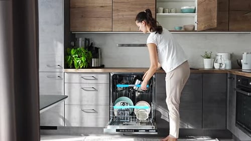 Woman Unloads Dishwasher in Bright Modern Kitchen