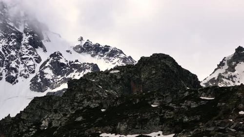 Snowcapped Mountain Peaks Emerging Through Misty Clouds in Stunning Panorama