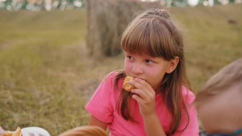 Little Kid Enjoying Snacks with Boy in Open Field Eating Pastries
