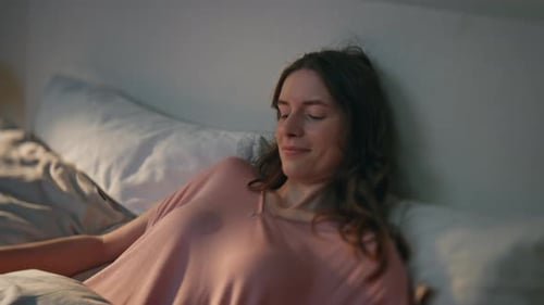Woman Smiling and Relaxing in Bed at Home