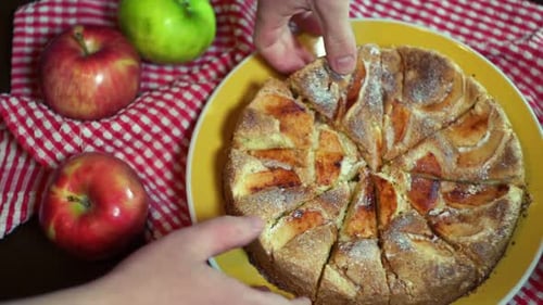 Sliced Apple Pie on Kitchen Table. Female and Male Hands Taking Out