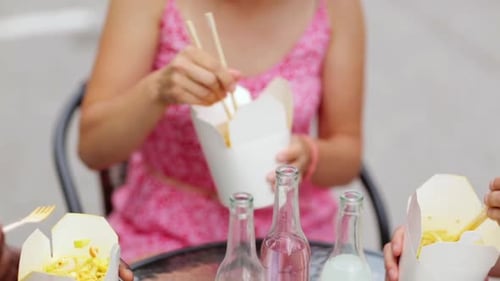 Friends Sharing Takeout Noodles and Toasting Drinks