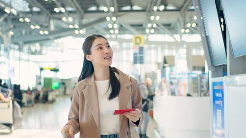 Asian young woman passenger checking depature boarding pass in airport.