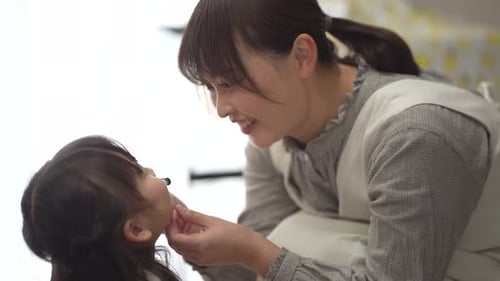 Woman Brushing Teeth of Young Girl Indoors