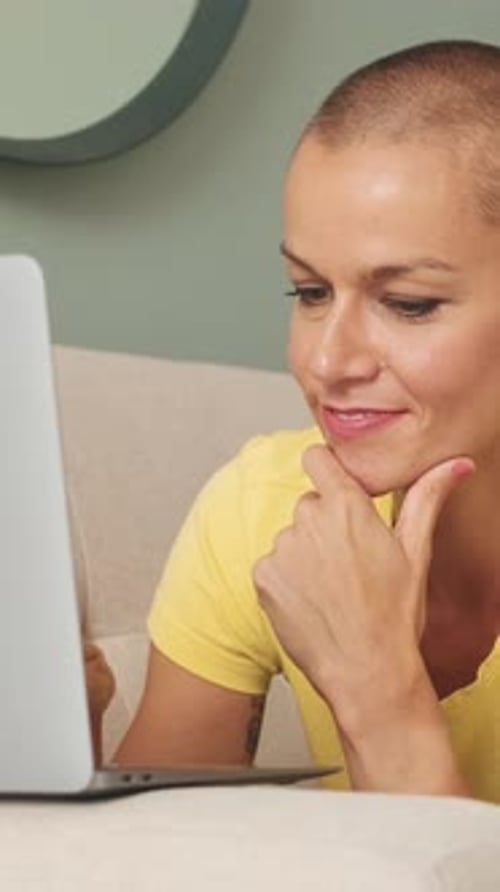 Woman with short hair looking at laptop on couch