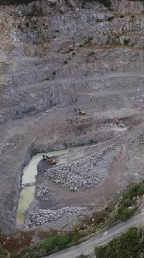 Vertical video of Trucks and a Bulldozer Quarrying in a Rock Quarry