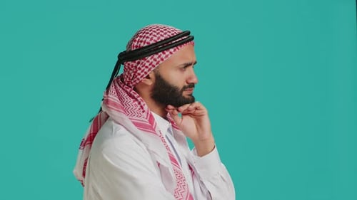 Man in Headdress Contemplating Against Blue Background