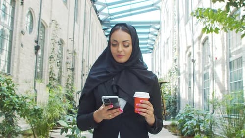 Portrait of Young and Confident Muslim Business Woman with a Smartphone and Coffee in Hijab Middle