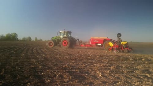 Green tractor works on the field sowing sunflower. Tractor planting corn in Ukraine