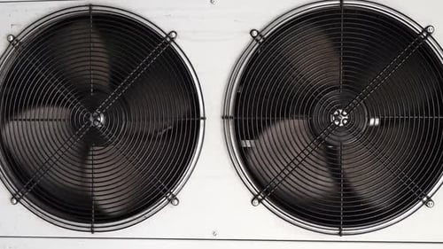 Close-up of Two Industrial Fans Spinning in a White Enclosure