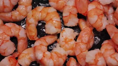A close-up of pan-fried shrimp. Large shrimp are fried in oil.