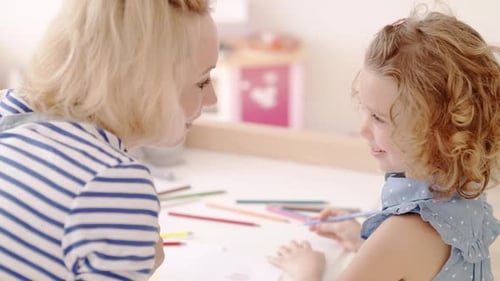 Woman and Girl Drawing Together at Table Indoors