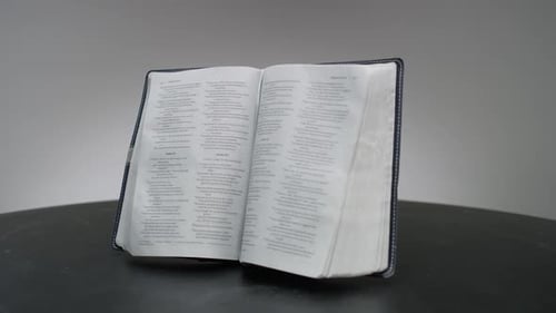 Open Bible in Center on Black Surface