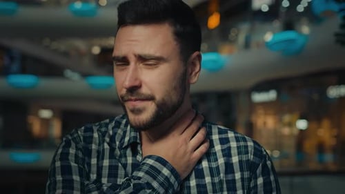 Worried Man with Sore Throat in Shopping Mall