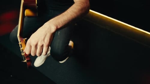 Young Musican Man Checking Strings of Acoustic Guitar Closeup Male Guitarist Tuning Sound of Musical