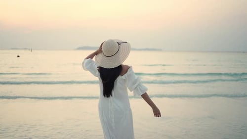 4K Young Asian woman walking on tropical island beach at summer sunset