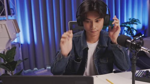 Young livestream host starting show with microphone and headphones in home studio
