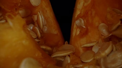 Halved Orange Pumpkin with Seeds on Cutting Board