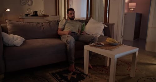 Man Relaxes on Couch with Beer and TV
