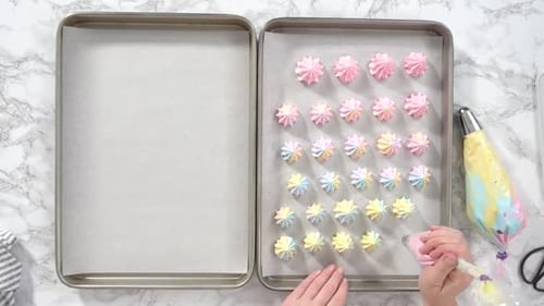 Baker Piping Pastel Meringue Cookies on Baking Sheet