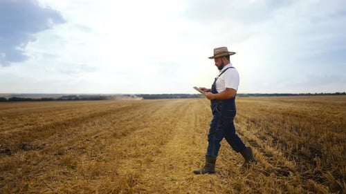 Farmer Walking Across Field Using Tablet Device