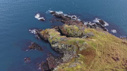 Rocky coastline and clear water captured from above during sunny day