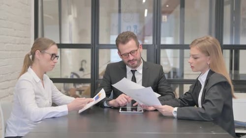 Team Discussing Documents and Tablet in Office