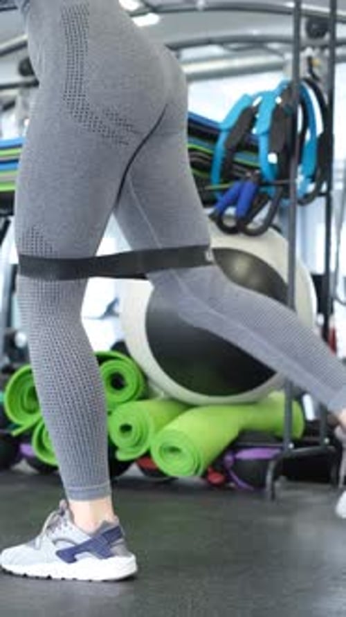 Woman Doing Leg Extension with Resistance Band at Gym