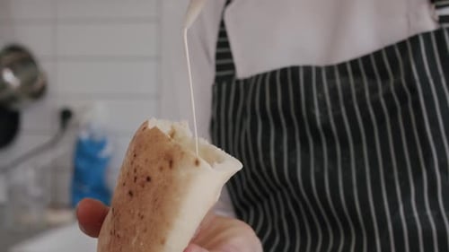 Adding Sauce to Pita Bread Inside Kitchen