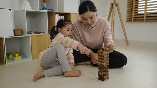 Woman and Girl Play Tower Game on Floor